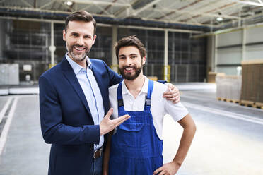 Portrait of happy businessman and worker in a factory - BSZF01254