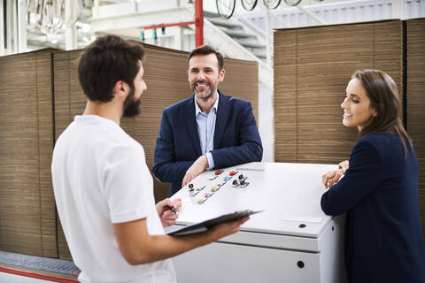 Geschäftsleute und Angestellte im Gespräch in einer Fabrik, lizenzfreies Stockfoto