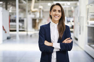 Porträt einer lächelnden Geschäftsfrau in einer Fabrik - BSZF01272