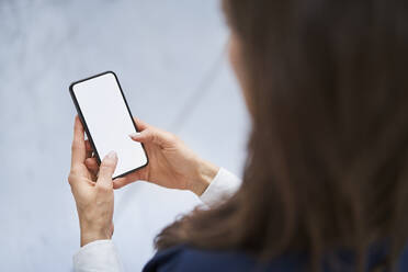 Close-up of businesswoman holding cell phone in factory - BSZF01275