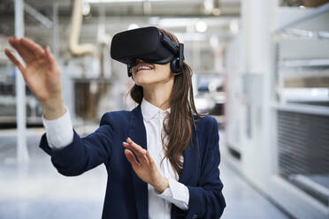 Businesswoman wearing VR glasses in factory - BSZF01276