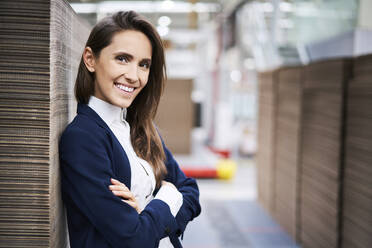 Porträt einer lächelnden Geschäftsfrau in einem Fabriklager - BSZF01283