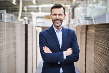 Porträt eines lächelnden Geschäftsmannes in einem Fabriklager - BSZF01289