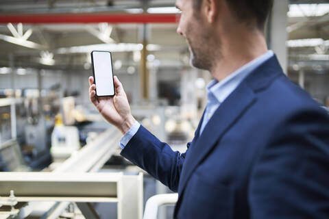 Businessman using cell phone in factory stock photo
