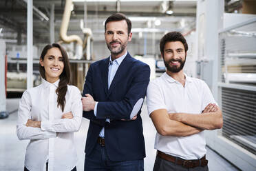 Portrait of confident businessman and employees in a factory - BSZF01308