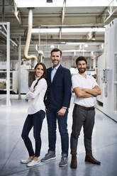 Portrait of confident businessman and employees in a factory - BSZF01309