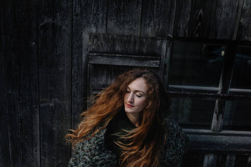 Porträt einer rothaarigen Frau mit geschlossenen Augen, Holzwand im Hintergrund - OGF00086