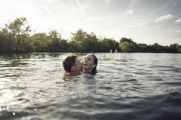 Affectionate couple swimming together in a lake - GUSF02304