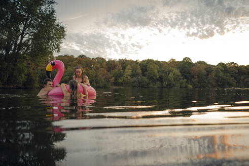 Friends having fun on a lake on a pink flamingo floating tire - GUSF02324