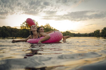 Friends having fun on a lake on a pink flamingo floating tire - GUSF02325