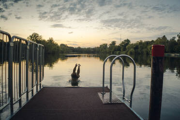 Young man jumping from jetty into the lake - GUSF02329