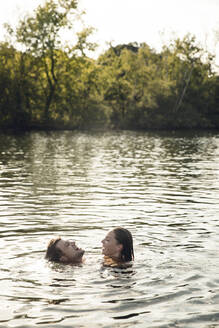 Affectionate couple swimming together in a lake - GUSF02342