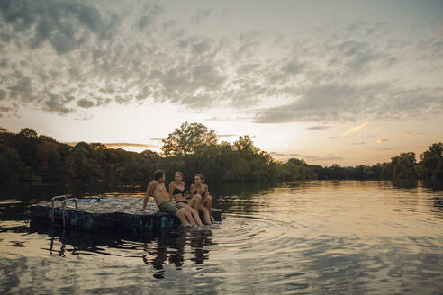 Friends having fun at the lake, sitting on bathing platform - GUSF02366