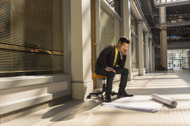 Gemischtrassiger Mann liest Baupläne in einem Gebäude - BLEF12994
