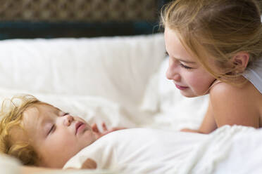 Kaukasisches Mädchen und Kleinkind Bruder auf dem Bett liegend - BLEF13020