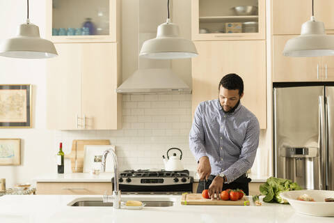Gemischtrassiger Mann beim Kochen in der Küche, lizenzfreies Stockfoto