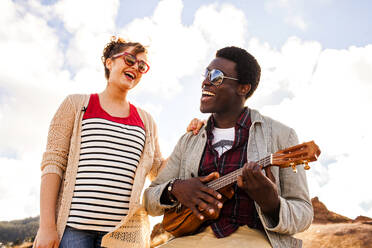 Couple singing together and playing ukulele outdoors - BLEF13122
