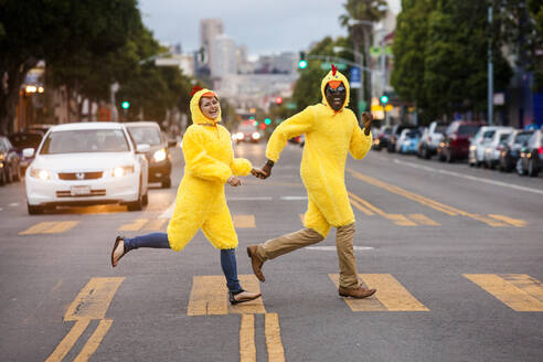 Couple in chicken costumes crossing city street - BLEF13128