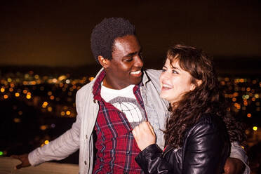 Couple hugging near scenic view of cityscape at night - BLEF13136