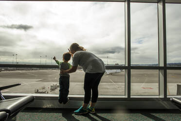Mutter und Sohn schauen aus dem Flughafenfenster - BLEF13139