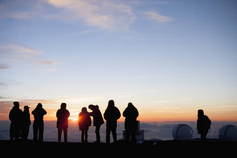 Silhouette von Touristen, die die Aussicht vom Berggipfel bewundern, Kilauea, Hawaii, Vereinigte Staaten, lizenzfreies Stockfoto