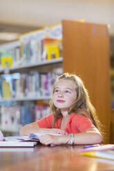 Kaukasischer Student sitzt am Schreibtisch in der Bibliothek - BLEF13282