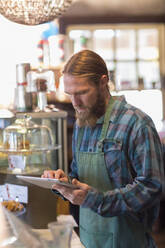 Kaukasischer Server mit digitalem Tablet in einem Café - BLEF13344