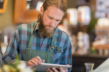 Kaukasischer Server mit digitalem Tablet in einem Café - BLEF13346