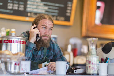 Kaukasischer Server beim Telefonieren in einem Cafe - BLEF13352