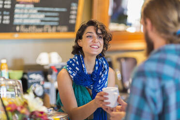 Server giving cup of coffee to customer in cafe - BLEF13359