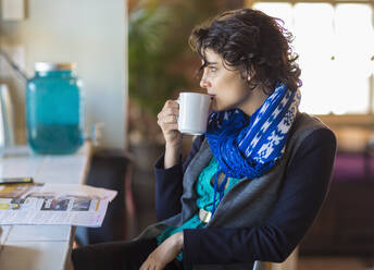 Gemischtrassige Frau trinkt eine Tasse Kaffee in einem Cafe - BLEF13364