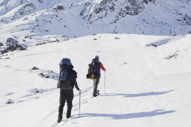 Hispanic hikers walking on snowy mountain - BLEF13374