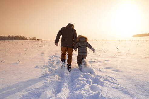 Mari Vater und Sohn spazieren im verschneiten Feld - BLEF13385