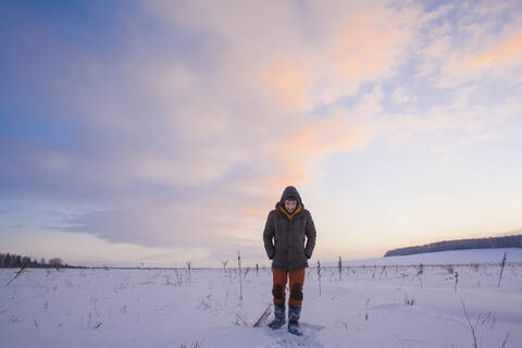 Gemischtrassiger Mann geht in verschneitem Feld, lizenzfreies Stockfoto