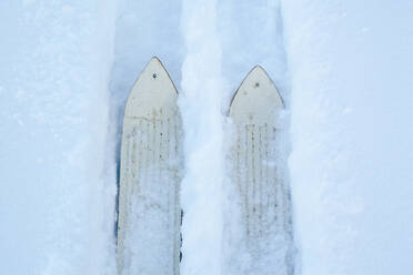 Hochformatige Ansicht von Skiern, die Spuren im Schnee ziehen - BLEF13411