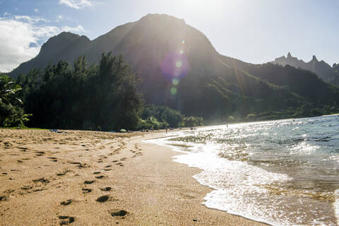 Fußabdrücke auf Sand in der Nähe von Wellen an einem tropischen Strand, lizenzfreies Stockfoto