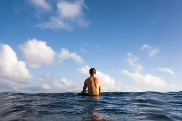 Surfer sitzt auf einem Surfbrett im Meer - BLEF13434