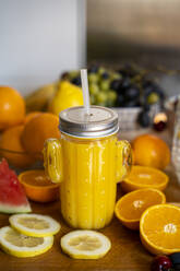 Orangen-Smoothie auf dem Küchentisch mit verschiedenen Früchten - AFVF03604