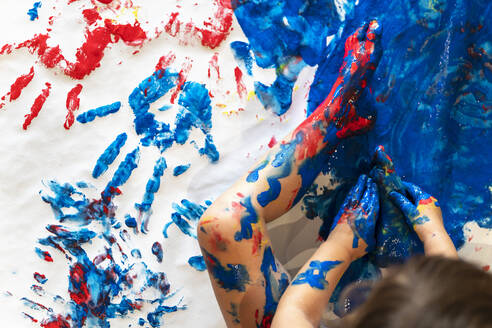 Kleinkind Mädchen sitzt auf Papier auf dem Boden spielen mit Fingerfarbe, Teilansicht - GEMF03026