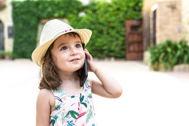 Porträt eines kleinen Mädchens mit Strohhut am Telefon - GEMF03031