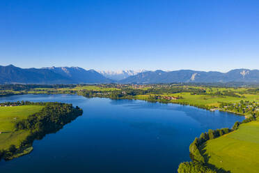 Scenic view of Riegsee lake and green landscape against clear blue sky, Germany - LHF00659