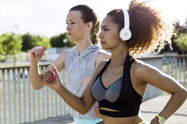 Zwei sportliche junge Frauen laufen auf einer Brücke - JSRF00482