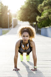 Sporty woman doing push-ups on a bridge - JSRF00497