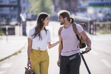 Young couple with electric scooter talking on the street - UUF18395