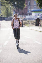 Young man riding electric scooter on the street - UUF18401