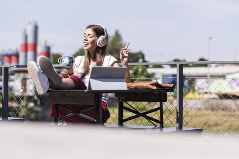 Young woman relaxing in a beer garden with headphones and tablet stock photo