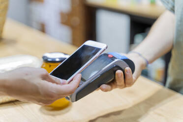 Customer paying cashless with smartphone in a shop - AFVF03611