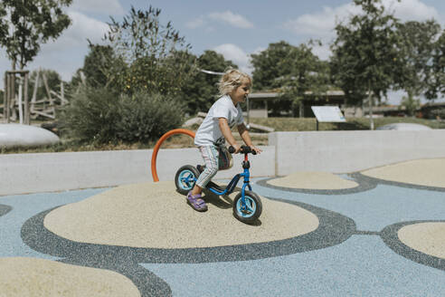 Glückliches Mädchen fährt Roller auf einem Spielplatz - DWF00453