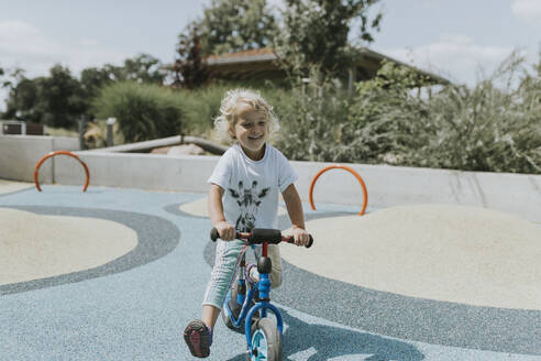 Glückliches Mädchen fährt Roller auf einem Spielplatz - DWF00455