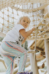 Mädchen klettert im Klettergerüst auf einem Spielplatz - DWF00456